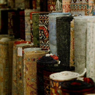 Photo by Şeyhmus Kino A variety of rolled carpets in vibrant colors and patterns on display in a textile shop.